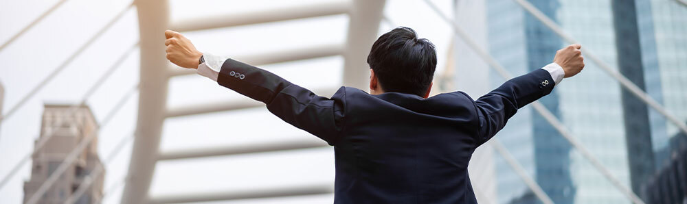 スーツ姿の男性が空に向かって両手を広げている画像